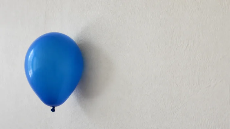 Açık renkli duvara statik elektrikle yapışmış mavi balon