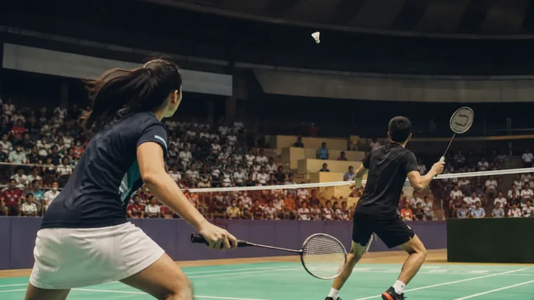 Yeni Delhi'de yazısız badminton dünya şampiyonası atmosferi: iki oyuncu rallide, tribünler arkada